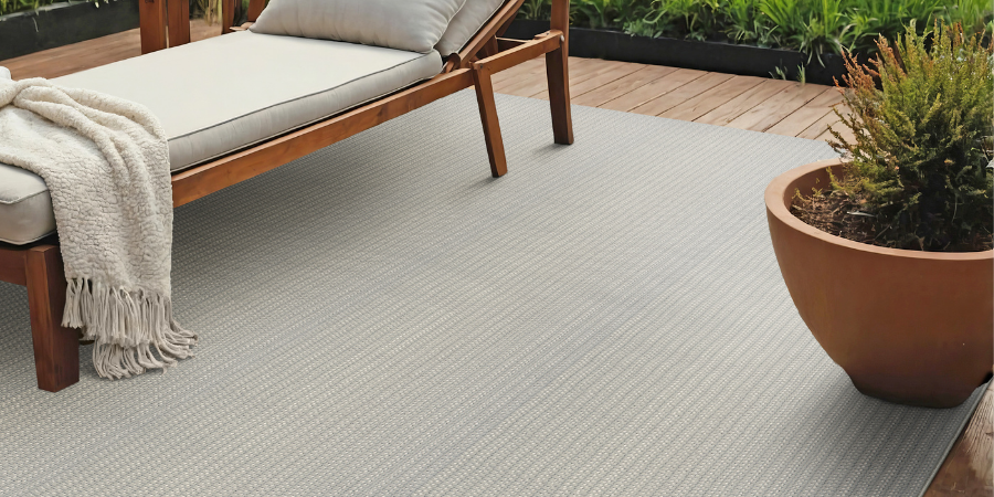 Custom outdoor rug on a deck next to a lounge chair 